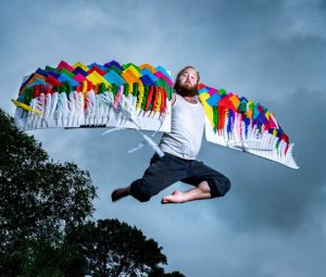 man jumping mid air with colourful wings