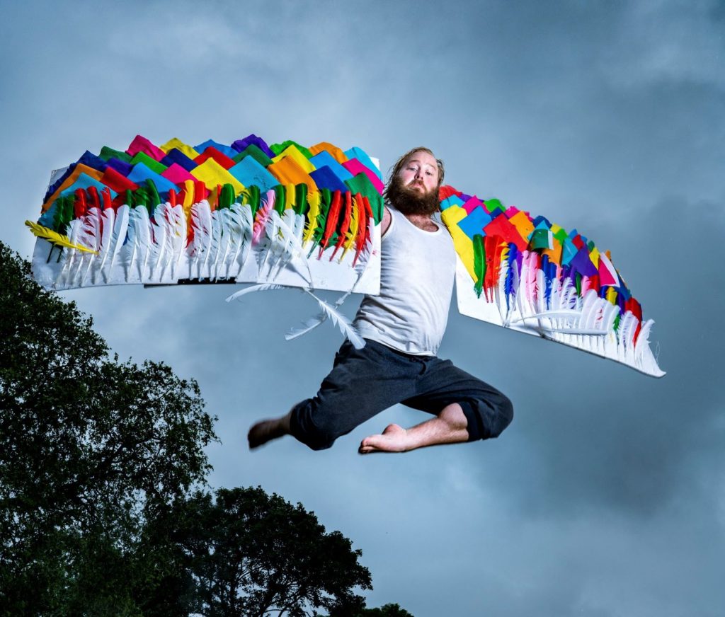 man jumping mid air with colourful wings
