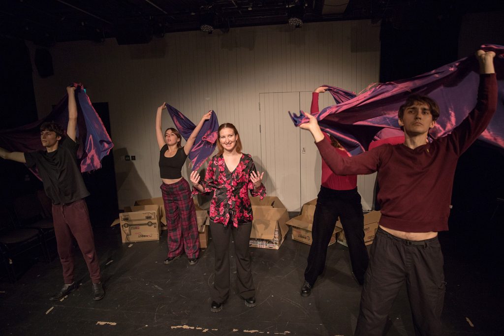 The 2023 cast of The S is Silent perform with red scarves at The Bush theatre.