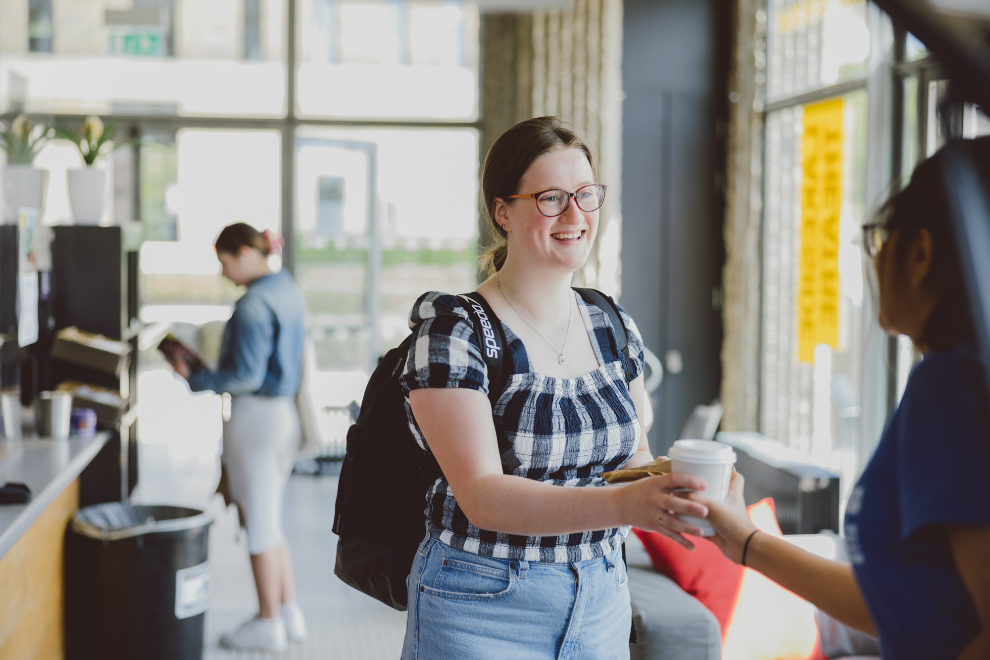 A young woman is handed her coffee by a member of the Lakeside Theatre Café team.