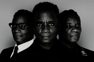 Rodreguez King-Dorset as three characters in Windrush Secret. The centre character is staring into the lens of the camera, with the other two characters flanking each shoulder.