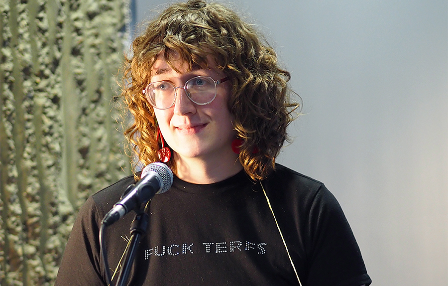 Alice K Stephens performing into a microphone at the Lakeside Theatre Café.