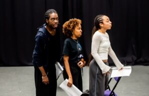 Three actors in a studio space, rehearsing the play Blacklist by Chileya Mwampulo. 